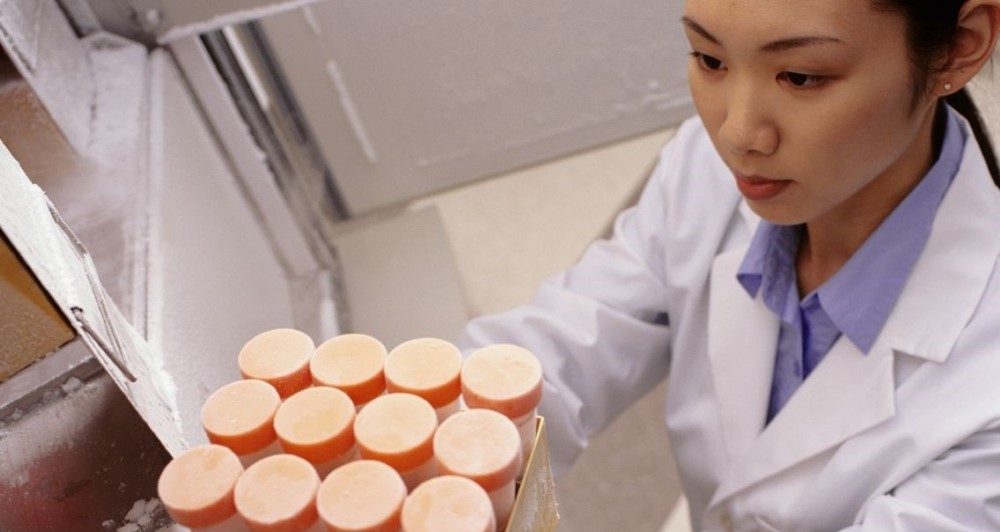 A photo of a laboratory worker placing products into an environmental freezer chamber.